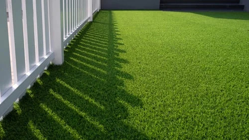 Freshly installed artificial turf lawn beside a white fence